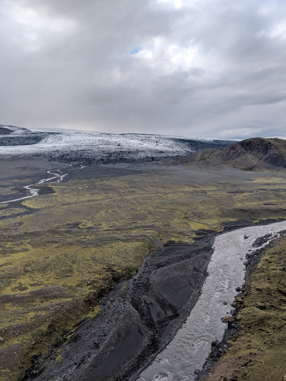 This is a picture of Öldusfellsjökull, an outlet glacier in southern Iceland. In front of the glacier a variety of glacial features can be seen: the two rivers in the image are fed by glacial meltwater (these create a variety of channelized sandy features – the black sediments on the bottom centre of the image), in the middle of the photo a variety of frontal and push moraines can also been seen (these were formed along ancient ice margins and tell us how much the glacier has retreated). 