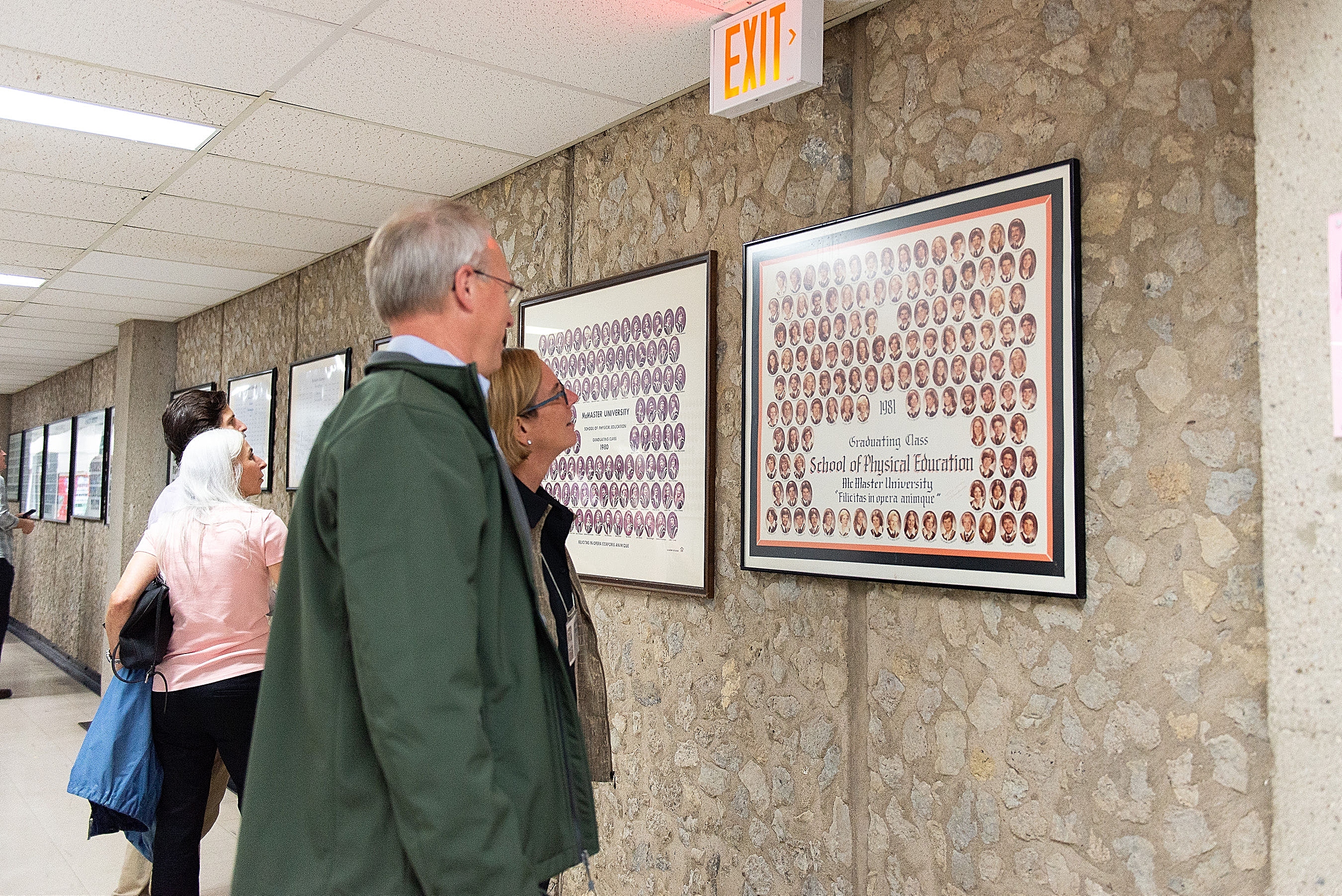 Alumni look at class photos in the hall of the Ivor Wynne Centre.