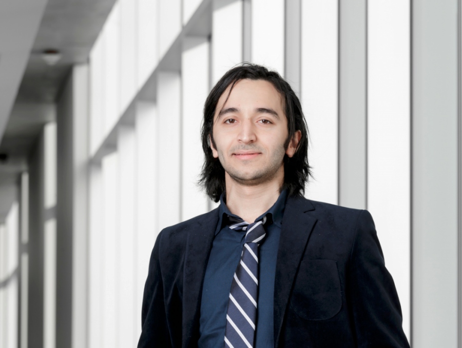 A young man in a jacket and tie looks at the camera