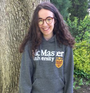 A smiling girl with long hair and glasses wearing a McMaster sweatshirt