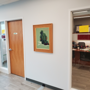 A photo of a hallway with two doors, one open and one closed. There is a framed painting on the wall. 