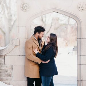 A couple hugging in front of the archway on McMaster's campus 