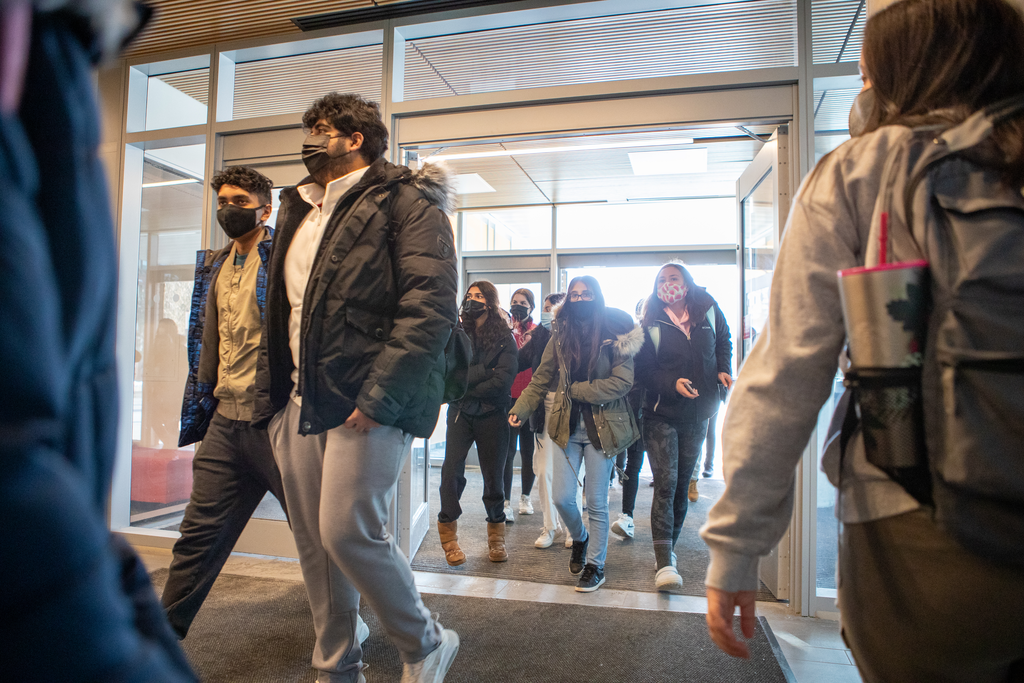 McMaster students step through a doorway into a campus building
