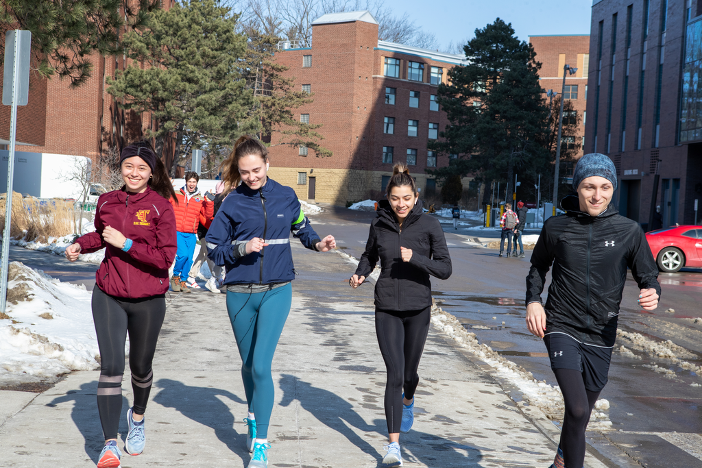 A group of four McMaster students run through McMaster's campus