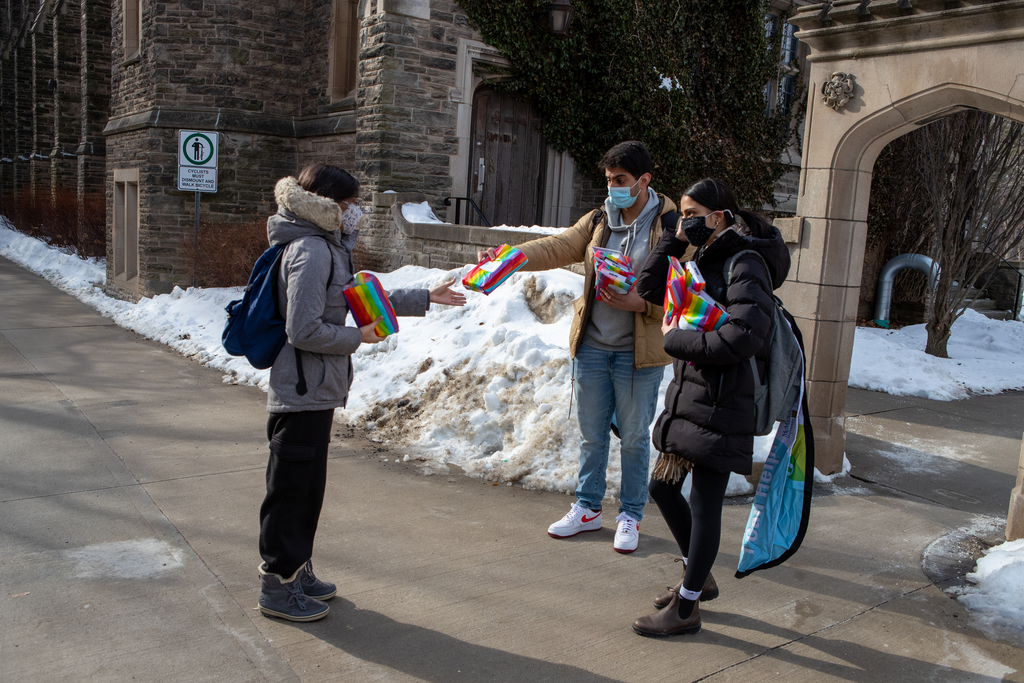Two McMaster students hand out rainbow-coloured welcome bags to students on campus
