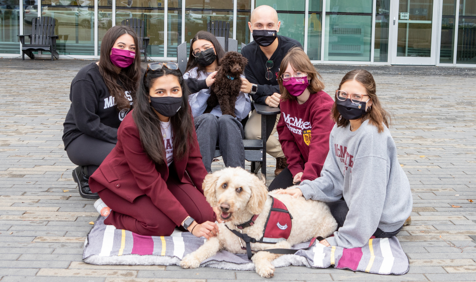 A group of McMaster students pose with two dogs 