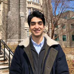 Adam El-Kadi smiling at the camera with McMaster University's campus behind him 