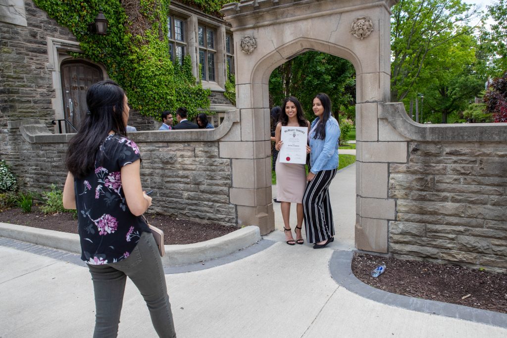 Two students pose for a photo in front of the Edwards Archway on McMaster's campus