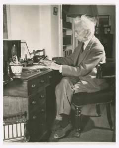 Bertrand Russell sitting writing at a desk