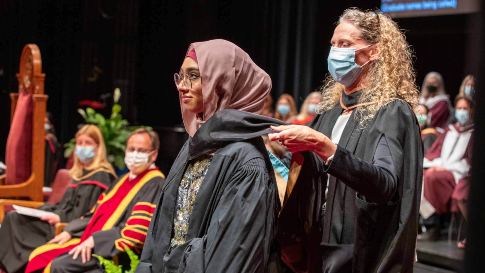 Melissa Pool places a stole on a nursing graduate 