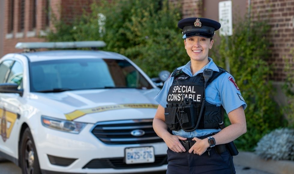 Melanie, a uniformed security officer, standing with a security car.