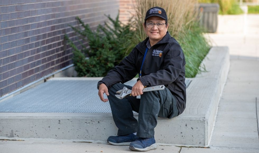 Norman sitting on the curb beside a flowerbed at McMaster