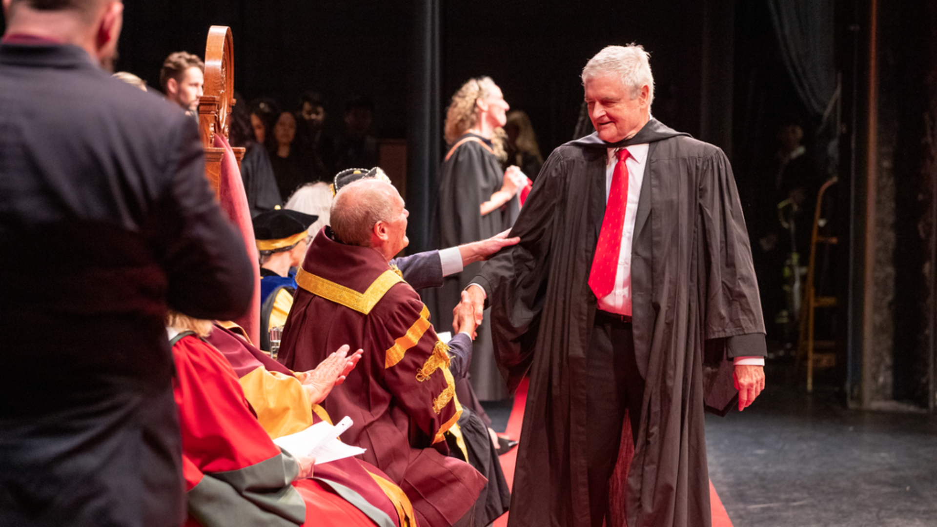 A graduate shakes the hand of David Farrar