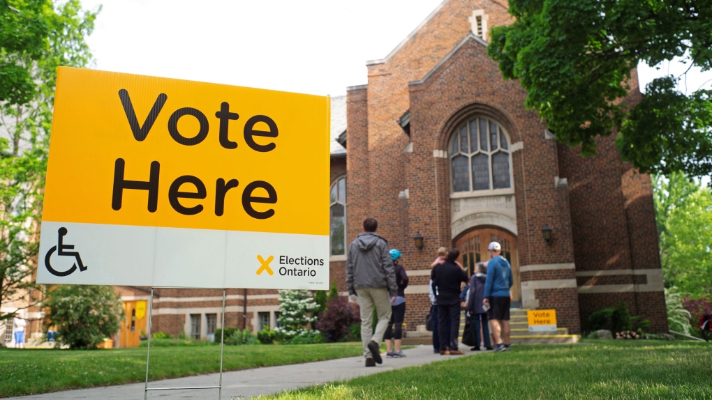 vote here yellow yard sign outside of voting at church with lineup outside