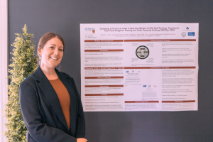 IUSRS participant Brittany Skov standing in front of a research poster smiling at the camera. 
