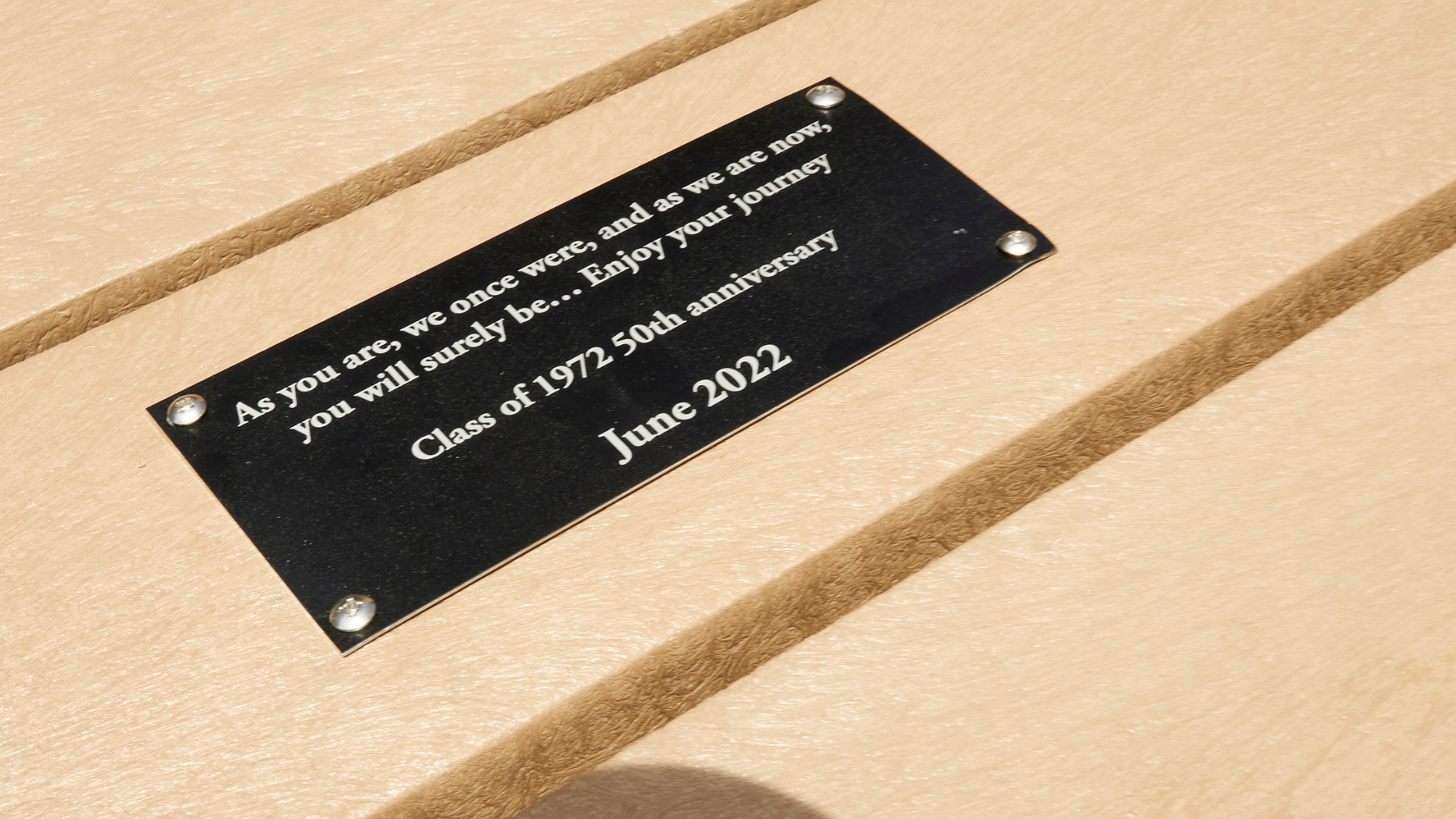 A plaque on a picnic table that reads 'As you are, we once were, and as we are now, you will surely be… Enjoy your journey. Class of 1972 50th anniversary – June 2022'