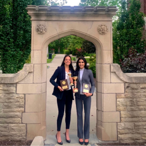 McMaster students Aivrey McKinley and Lesha Shah standing underneath the Edwards Arch on McMaster's campus holding two plaques and two awards. 