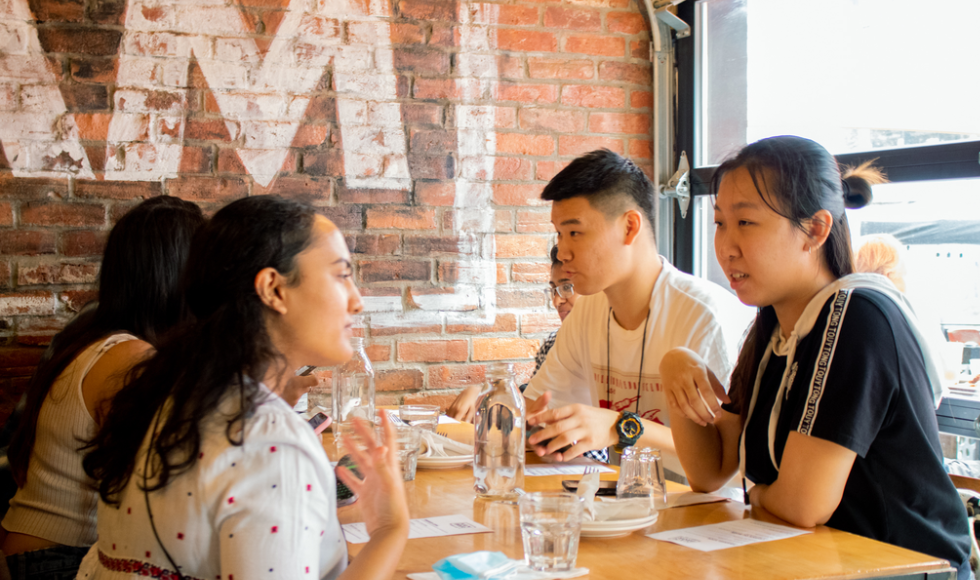 Five students sitting around a restaurant table 