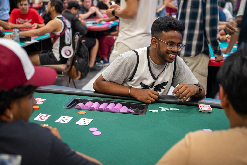 A student wearing a maroon MSU jersey seated at a casino dealer's table