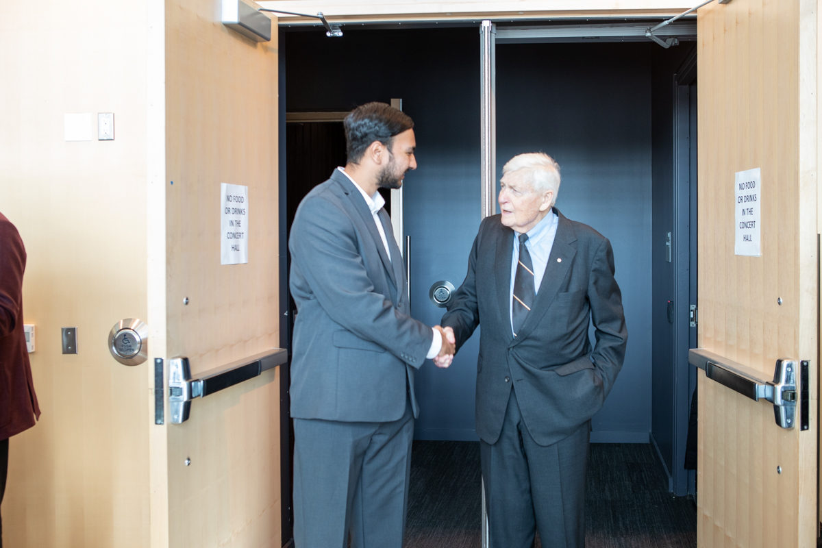 Simranjeet Singh, president of the McMaster Students Union, shakes hands with Lynton Wilson. 