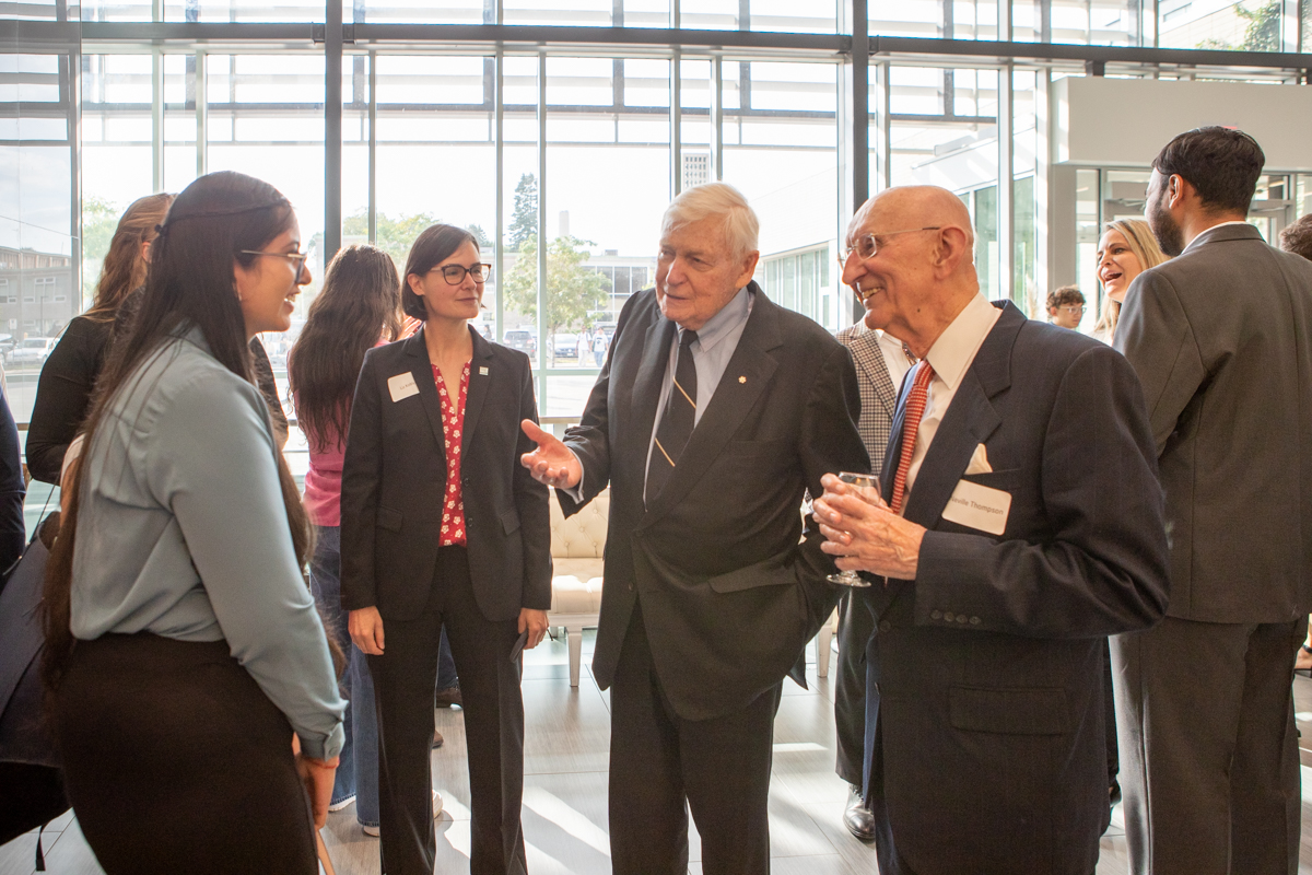 Lynton Wilson speaking to a student while two other people look on. 