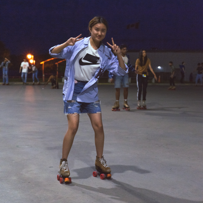 A student rollerskating and making peace signs at the camera with her hands