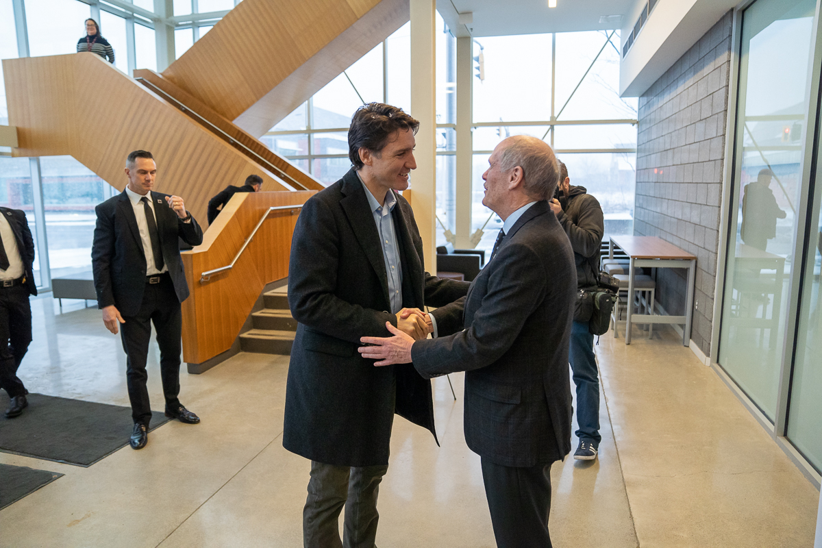 Prime Minister Justin Trudeau and McMaster President David Farrar greet one another in the foyer of the McMaster Automotive Resource Centre. 