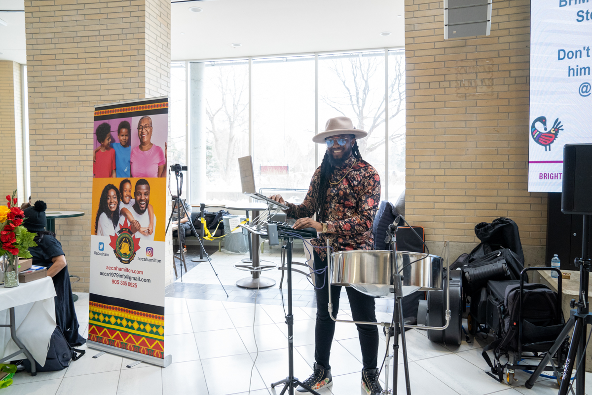 A DJ poses with his laptop and steelpan