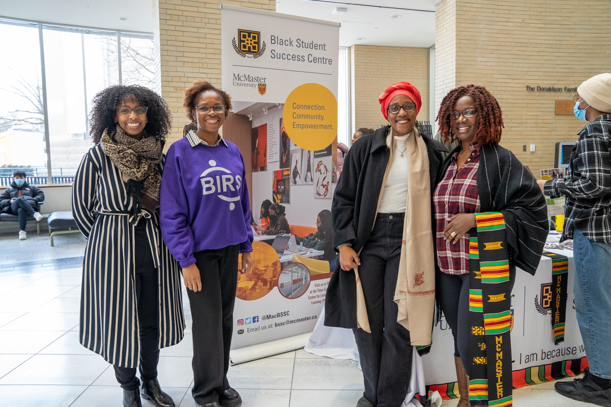 A group of professors and administrators pose in front of the Black Student Success Centre booth