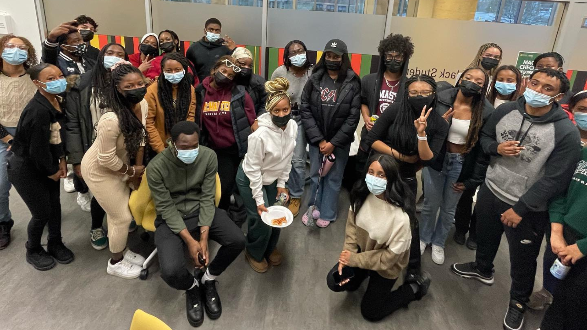 A group of students wearing masks and huddled together, posing for a photo