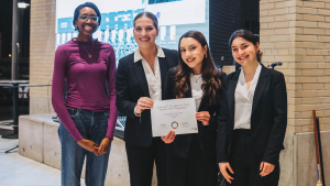 Four people smiling and posing for a photo. One of them is holding a certificate