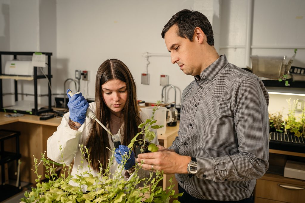 A student and professor examining a plant