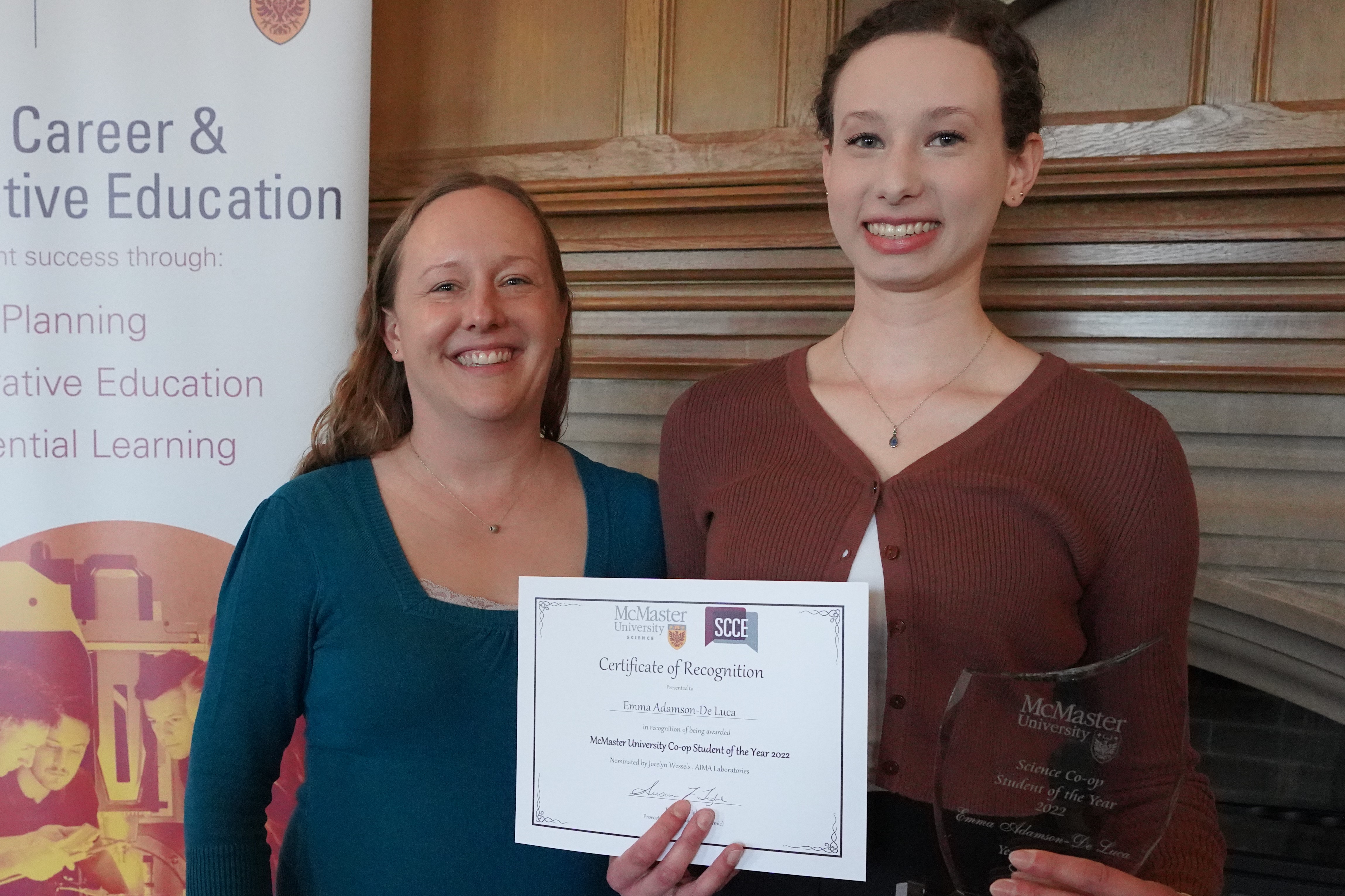 Two people smiling. One is holding a certificate. 