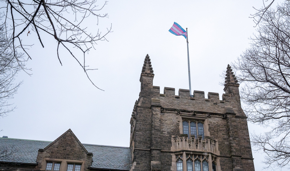 The pink, grey and blue striped trans flag flies above University Hall at McMaster