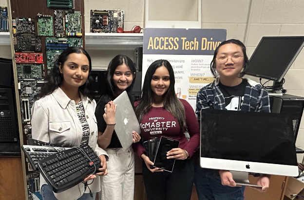 Four students holding donated tech in front of an Access Tech poster