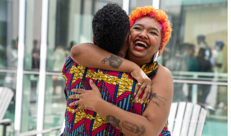 Graduating student Candace Walkes laughs as she hugs her sister Samantha, whose back is toward us.