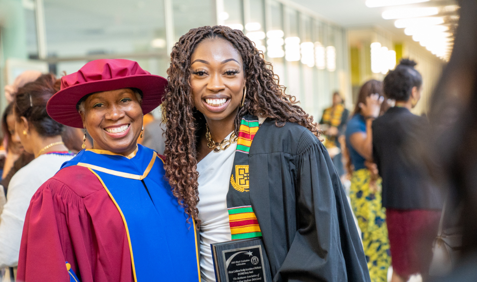 A smiling Prof Juliet Daniel and Student Renee Boney, both in academic robes, at the Black Excellence Graduation celebration.