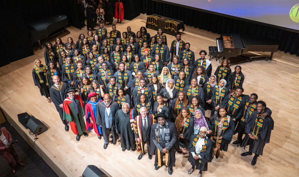 A group picture taken from above, of graduating students, faculty members, guests and university leaders at the Black Excellence Graduation celebration.