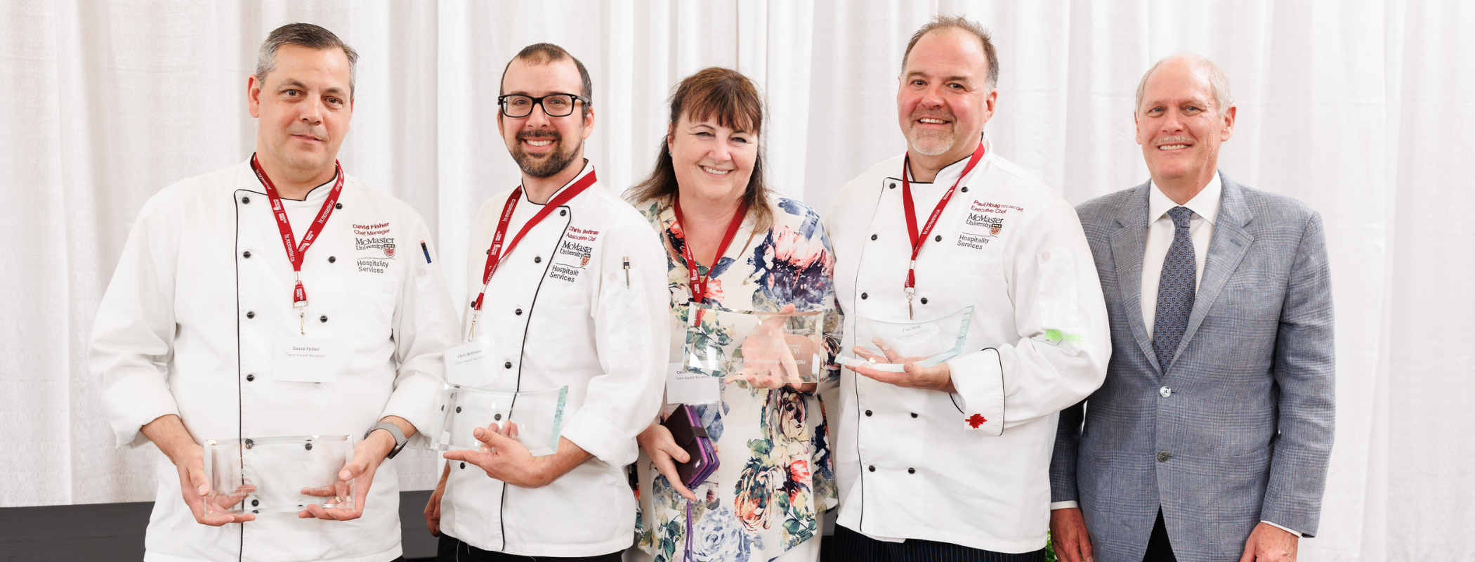 Five people posing for a photo. Three of them are in chef's whites. 