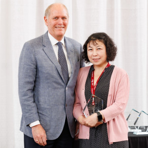 Lina Liu holding the President’s Award for Outstanding Service and posing for a photo with David Farrar