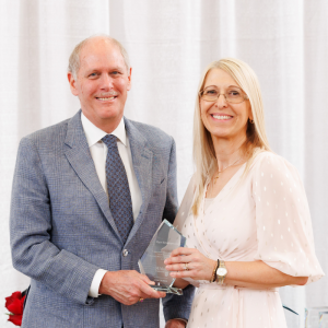 Mary Kiriakopoulos holding a President’s Award for Outstanding Service and posing for a photo with David Farrar