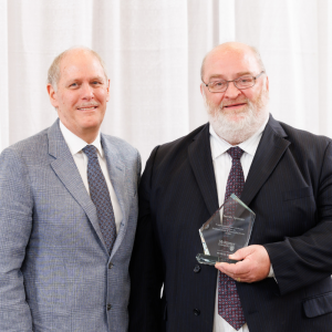 Steven Spencer holding a President’s Award for Outstanding Service and posing for a photo with David Farrar