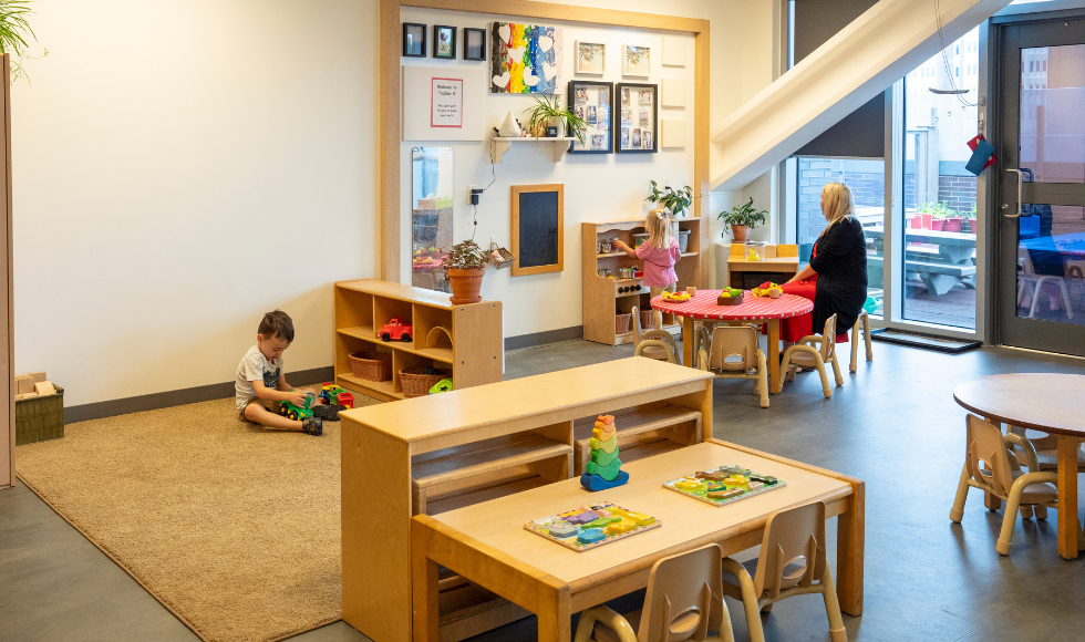 Two young children play while an adult looks on