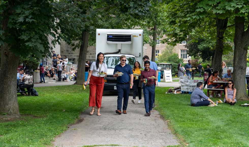 Employees walk down a path on BSB field at the employee picnic.