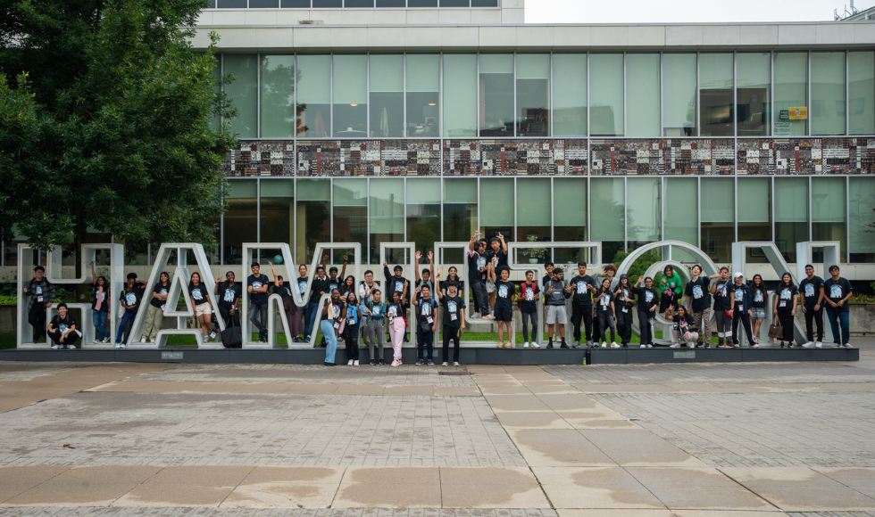 International students and Ignite program volunteers and family members at the Hamilton sign outside City Hall