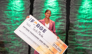 Shania Bhopa holds up a giant cheque for $15,000 that she won as Startup Survivor winner.