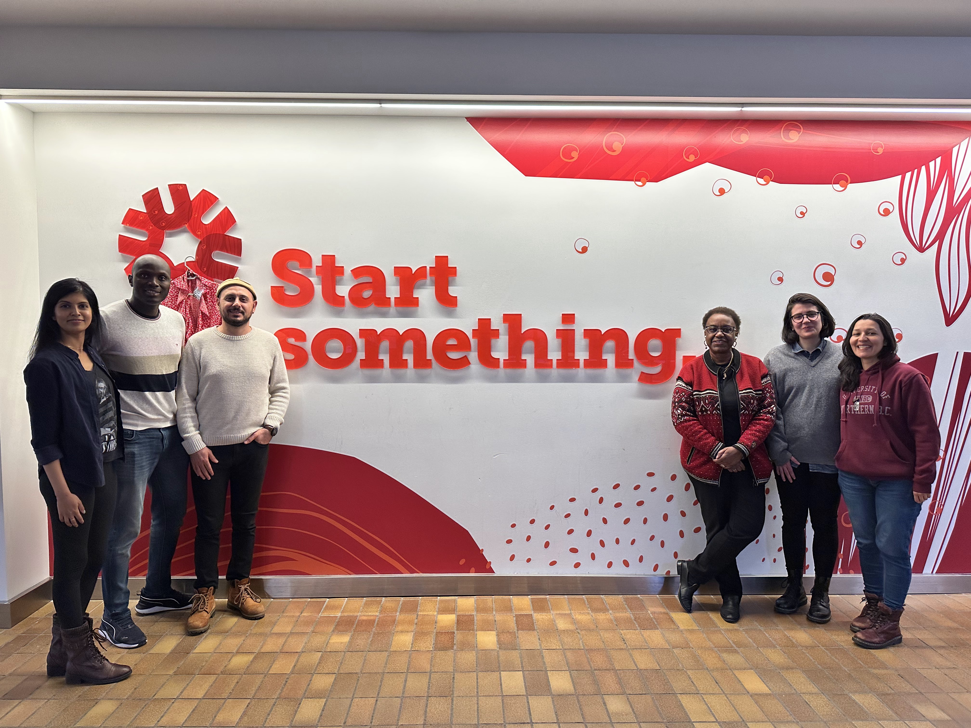 six individuals standing next to a banner that writes "start something"