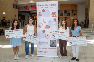 Four students holding signs advertising the 'Loonies for Lunches' campaign 