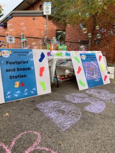 Tables set up outside an elementary school with art supplies, posters and snacks