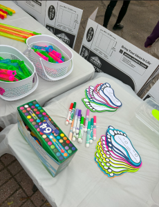 A table full of colourful markers, chalk and footprint cutouts for elementary school students. 
